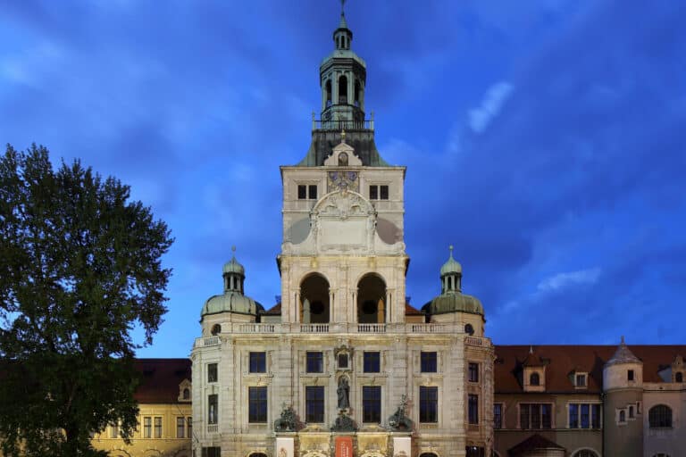 Die beleuchtete Fassade des Bayerischen Nationalmuseums in München bei Nacht.