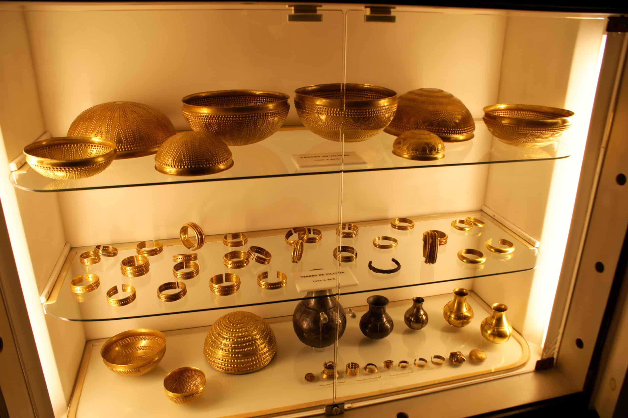 Goldene Schalen, Armreifen und Gefäße des Schatzes von Villena sind gemeinsam in einer Museumsvitrine angeordnet.