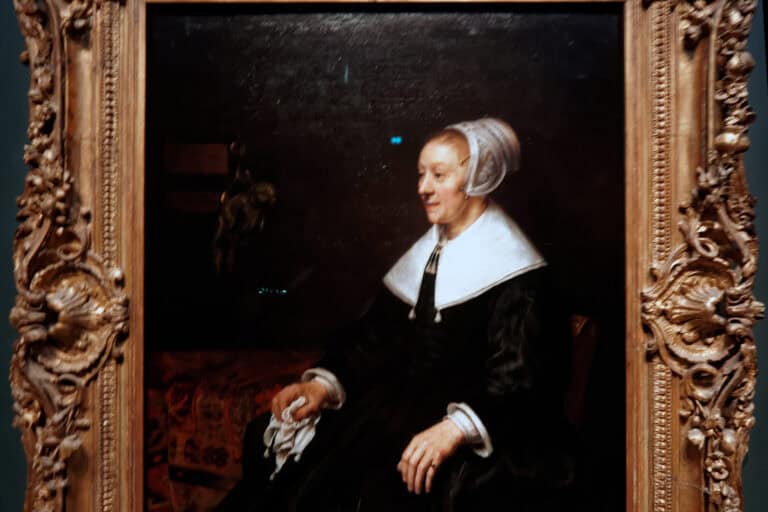 Catrina Hooghsaet sitzt in Rembrandts Porträt von 1657 mit schwarzem Seidenkleid und weißer Haube neben einem Sittich und hält ein Taschentuch.