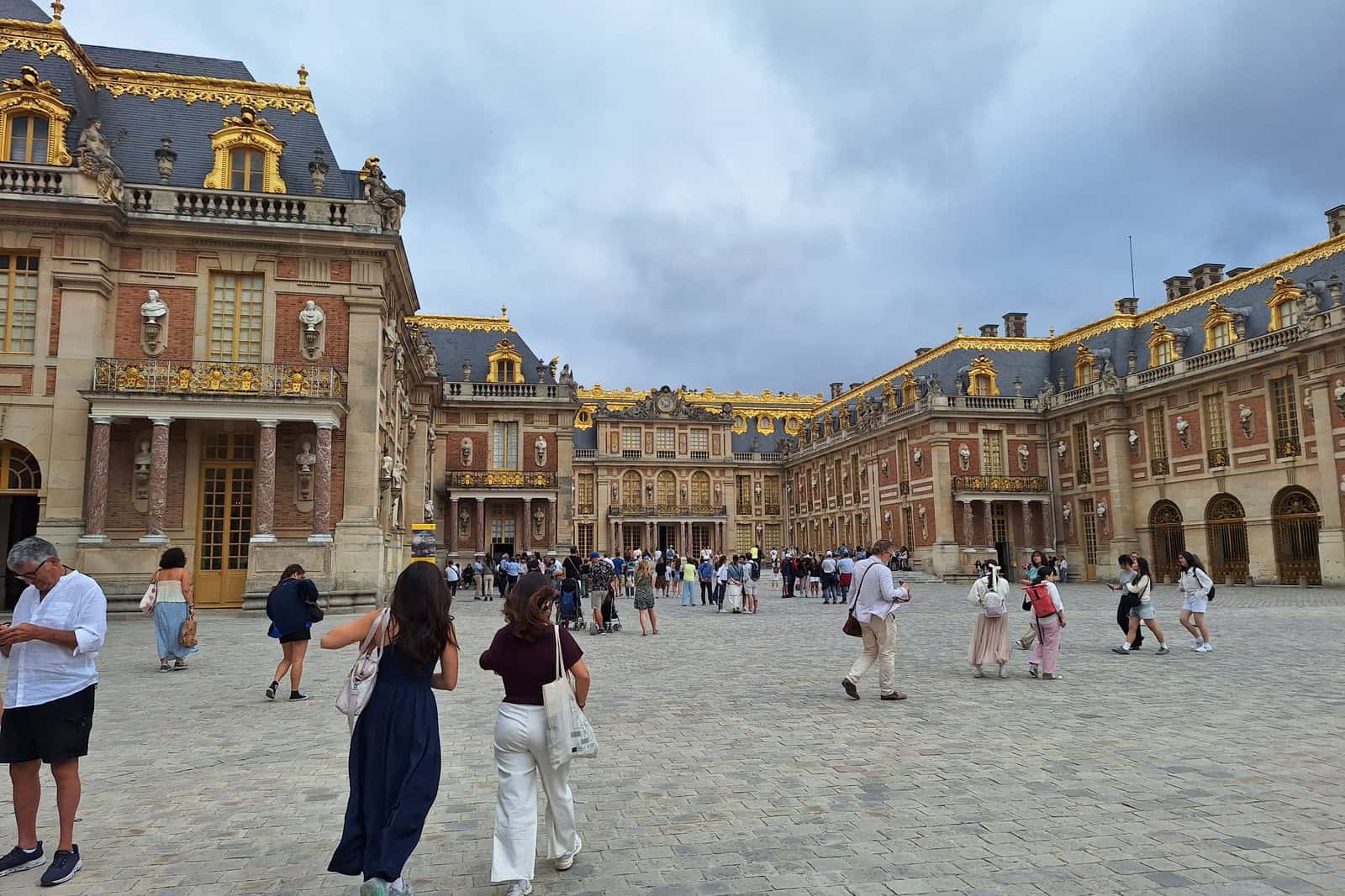 Fassade und Vorplatz des Schlosses Versailles bei Tageslicht.