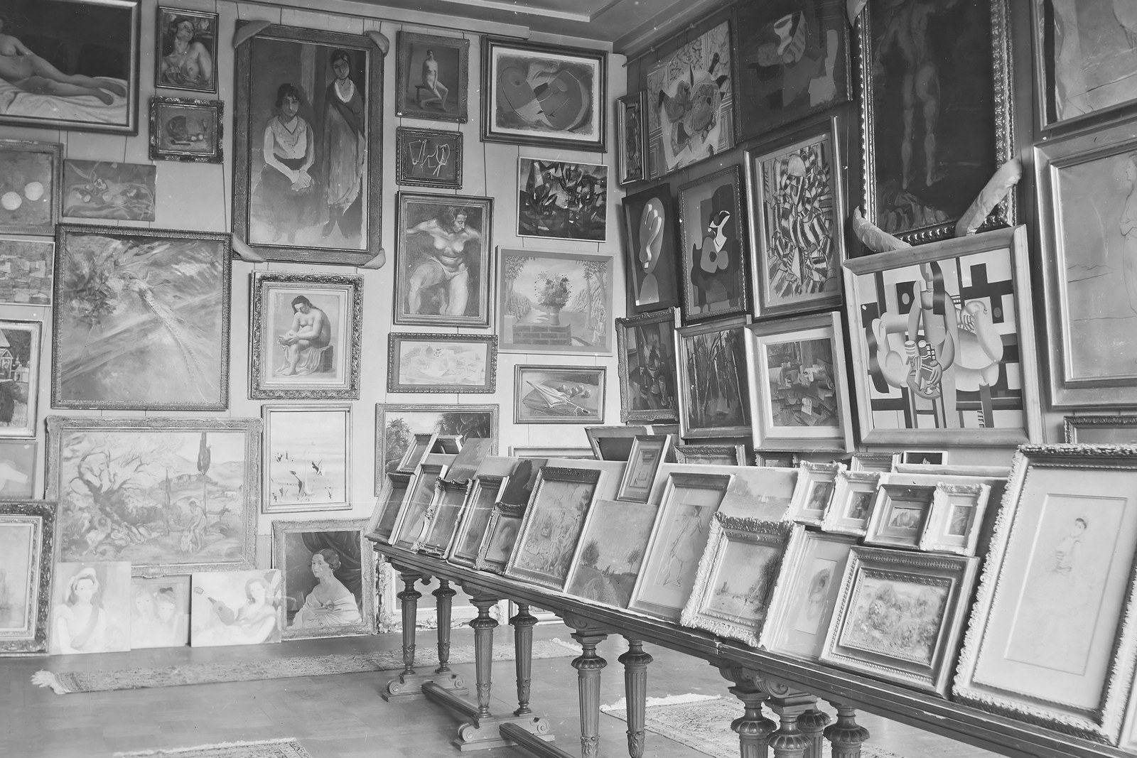 Schwarz-Weiß-Fotografie von 1940 mit dicht aufgestellten Gemälden in der Salle des Martyrs des Pariser Jeu de Paume.